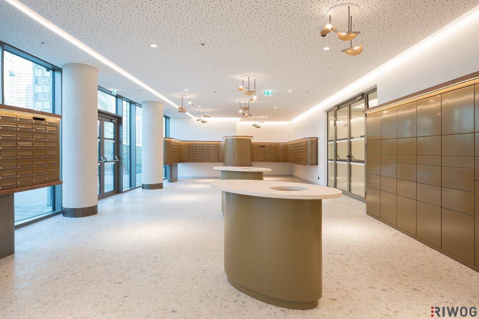 Helle, moderne Eingangshalle mit Postfächern, Sitzgelegenheiten und großen Fenstern.