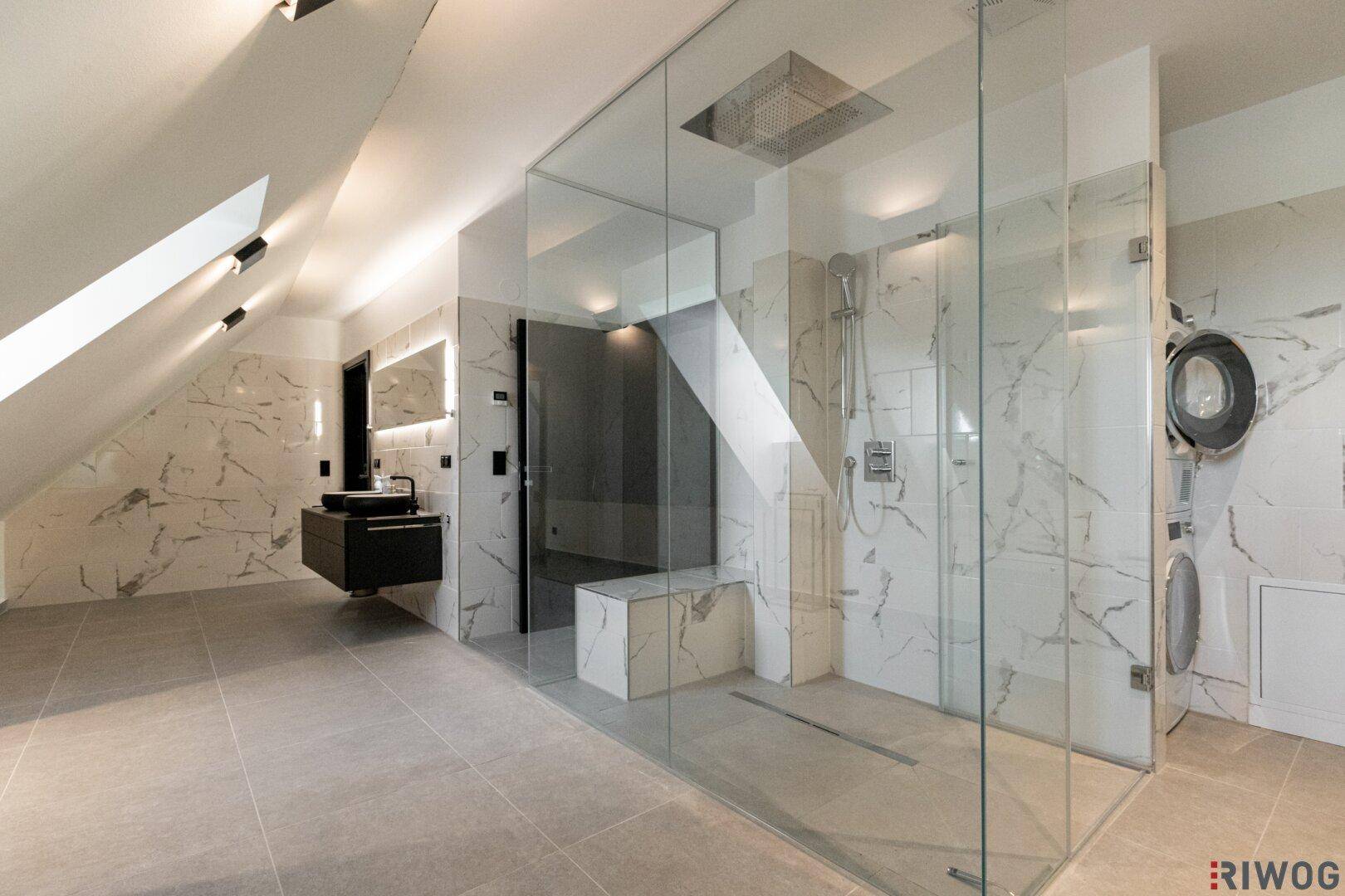 Großzügige begehbare Dusche mit Glasabtrennung, Regendusche und integrierter Waschküche.