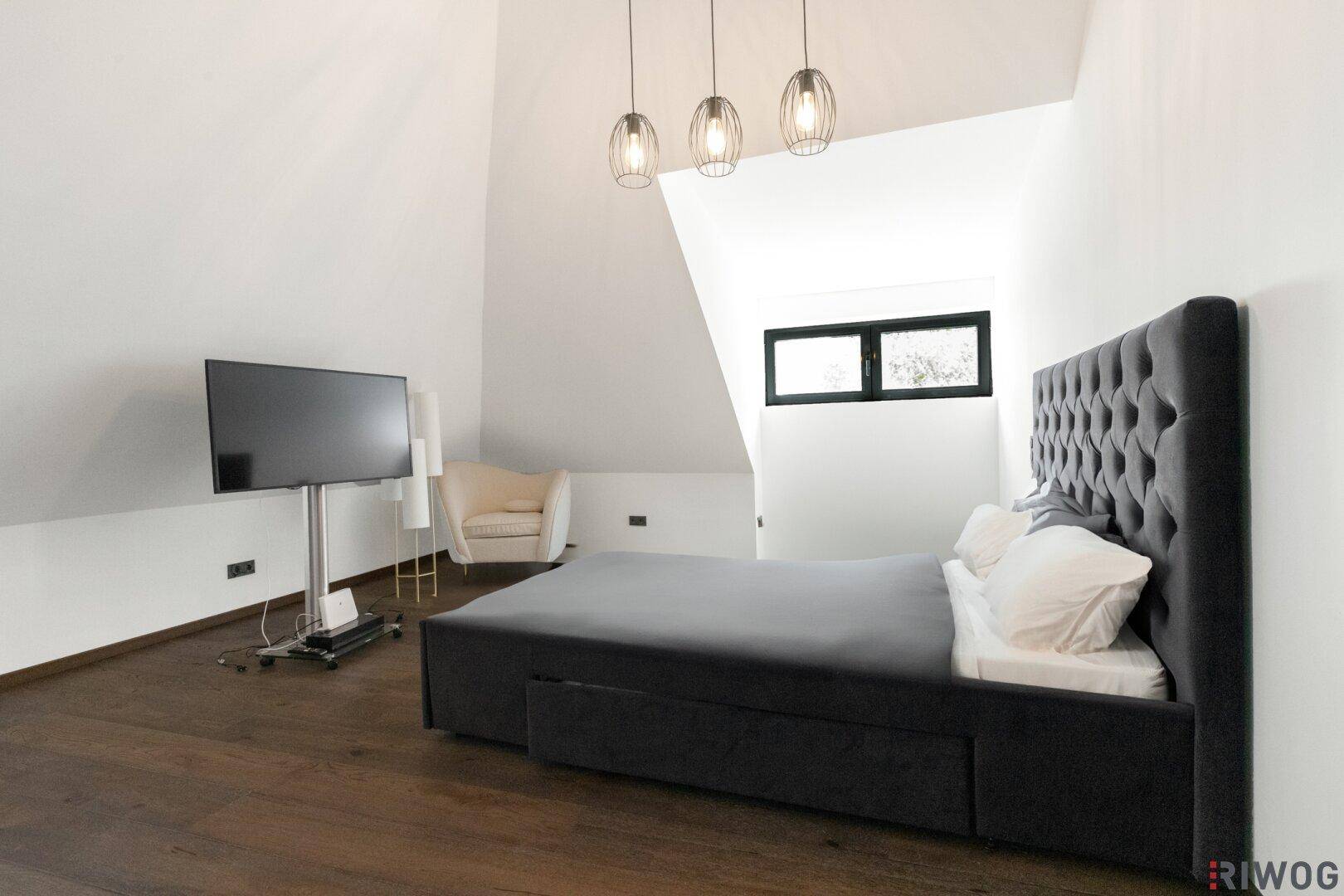 Modernes Schlafzimmer mit dunklem Holzboden, Dachschrägen und einem bequemen Bett.