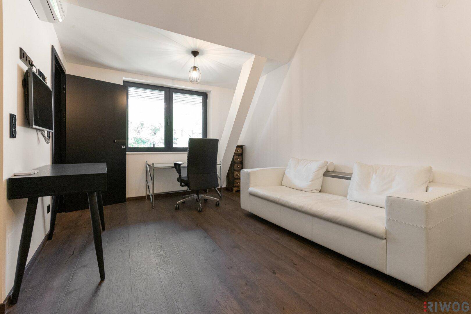 Funktionaler Arbeitsbereich mit Schreibtisch, Sofa, Holzboden und Klimaanlage.