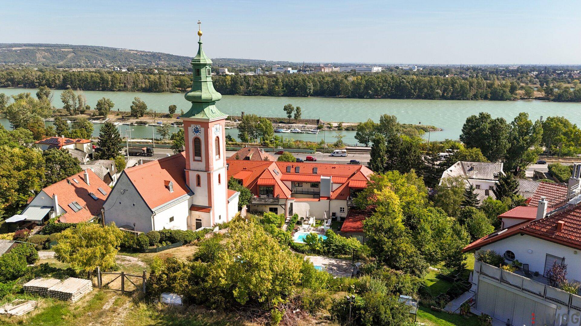 Panoramablick aus der Luft auf ein Dorf mit Kirche, Fluss und umliegender Landschaft.