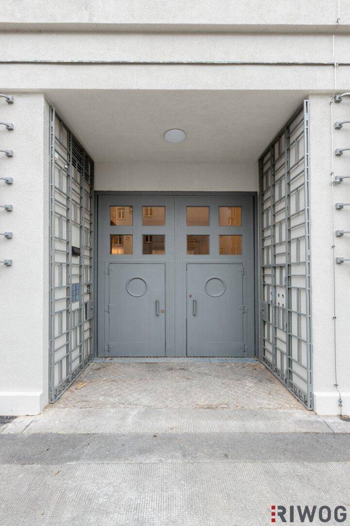 Der Haupteingang des Gebäudes mit zwei großen grauen Türen und dekorativen Metallgittern.