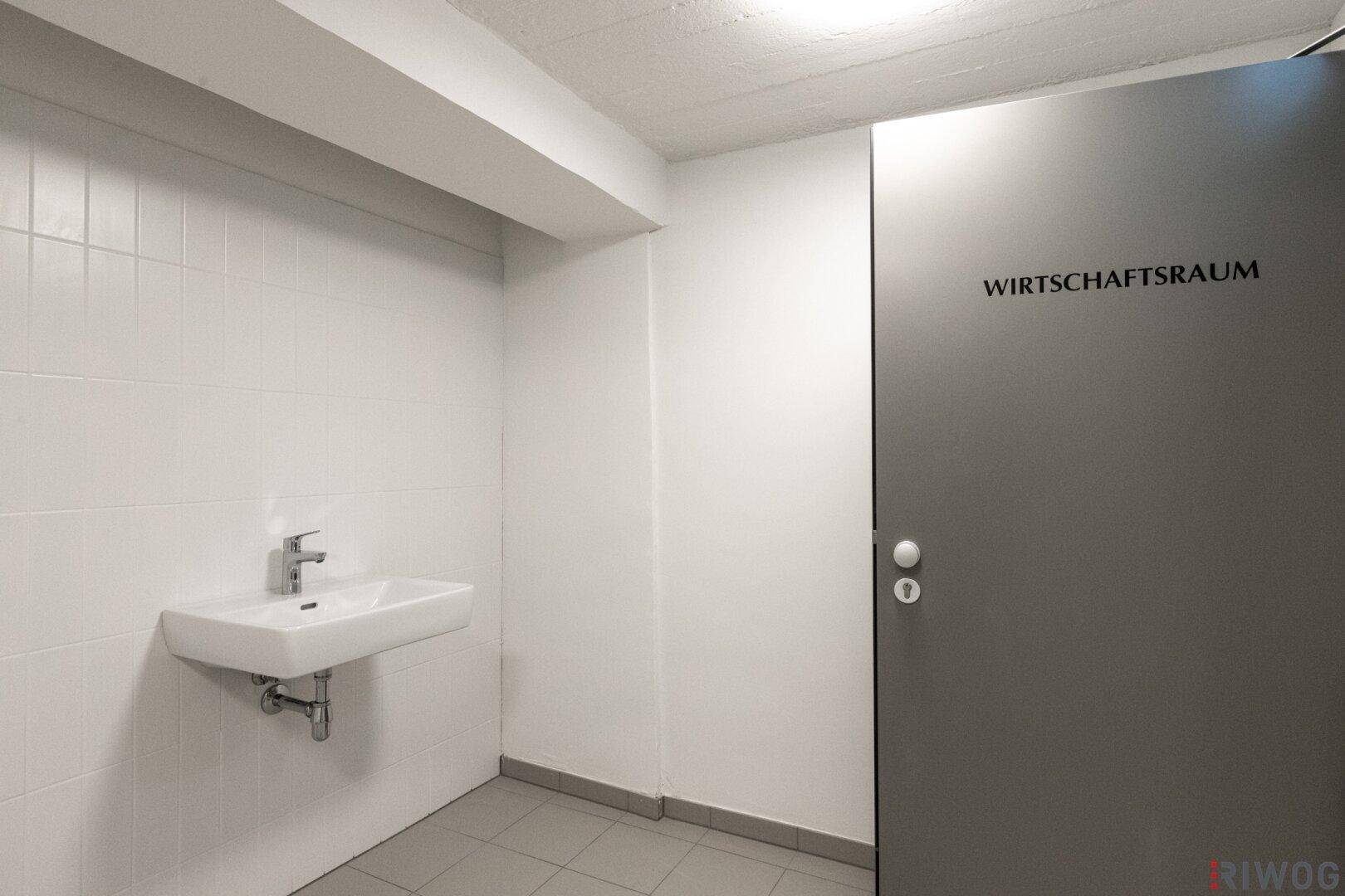 Kleiner Wirtschaftsraum mit Waschbecken und gefliesten Wänden, ideal für Hausarbeiten.