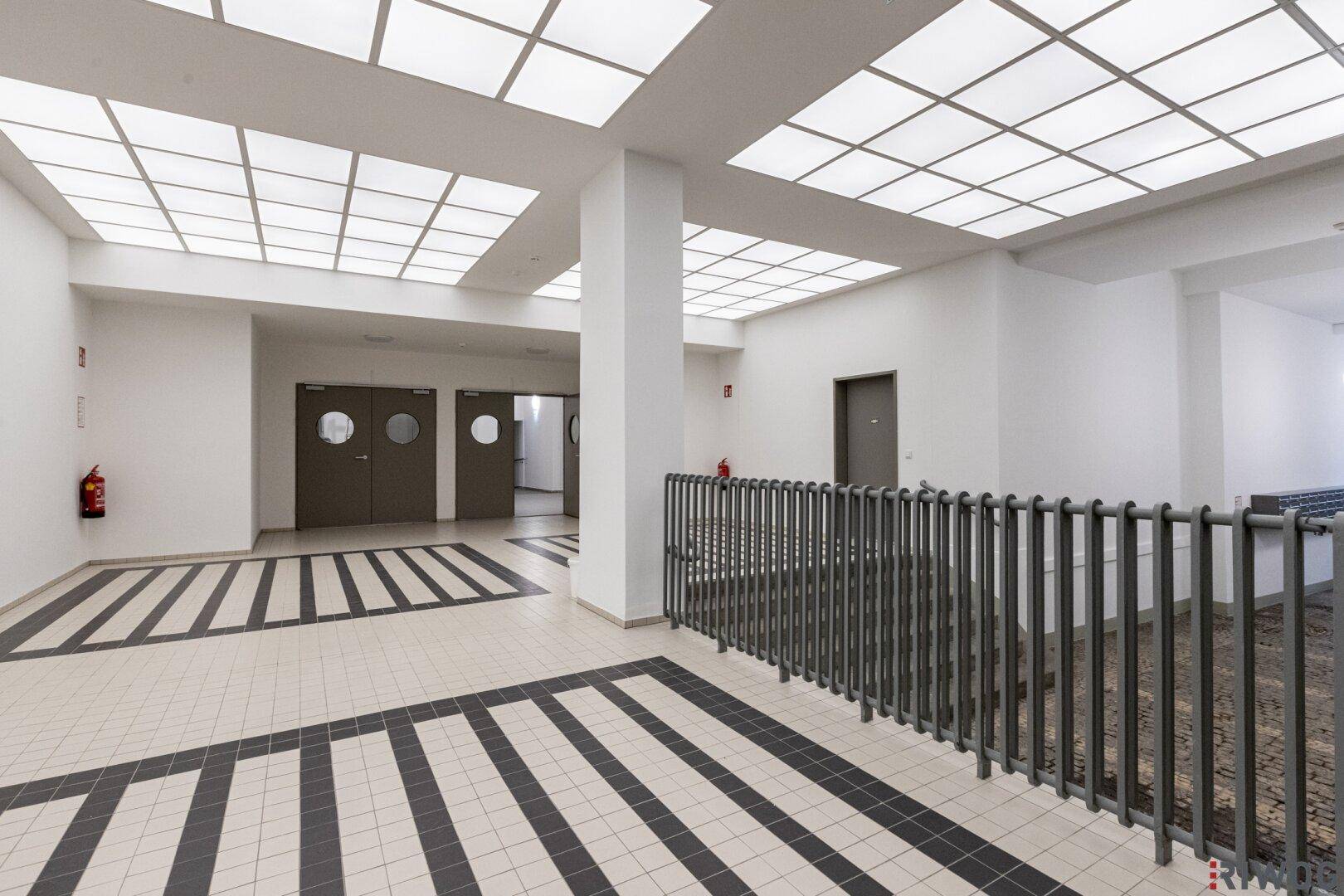 Moderner Flur mit auffälligem schwarz-weißem Fliesenmuster und Deckenbeleuchtung.