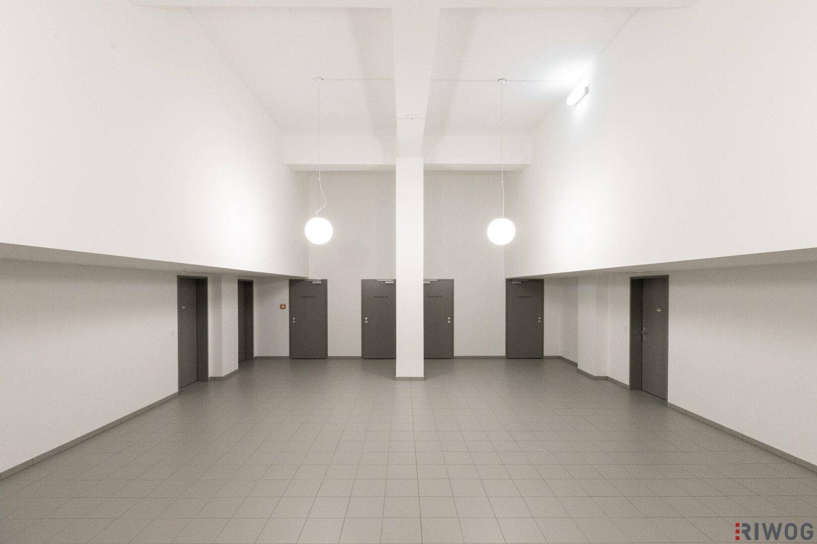 Geräumiger Flur mit Fliesenboden und mehreren Türen, gut beleuchtet.