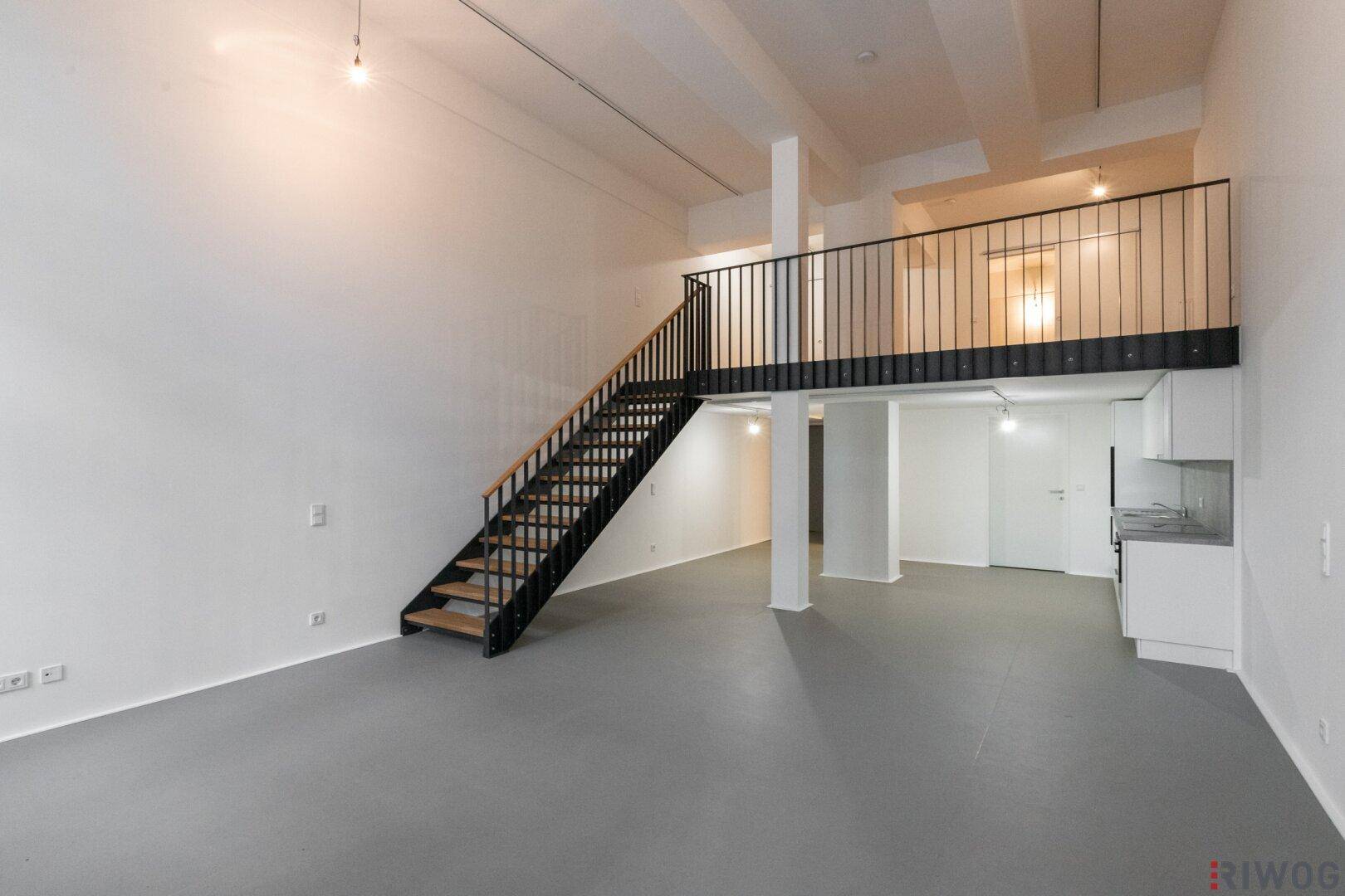 Großzügiger Loft-Raum mit offener Treppe zur Galerie und integrierter Küchenzeile.