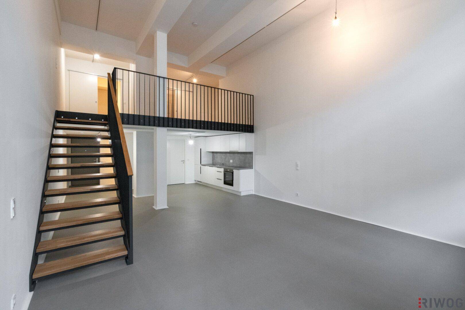 Heller Loft-Raum mit offener Treppe, Galerie und moderner Küchenzeile.