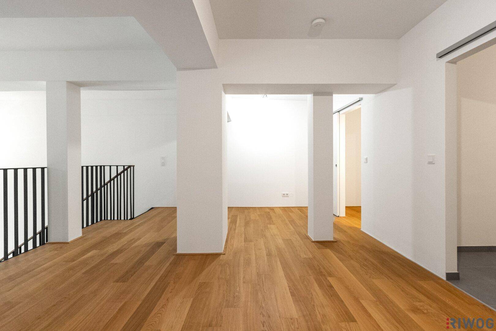 Offener Galeriebereich mit Holzfußboden und Blick auf die darunterliegenden Räume.