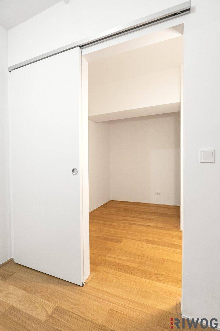 Heller Raum mit Holzfußboden und moderner Schiebetür, ideal als Schlaf- oder Arbeitszimmer.