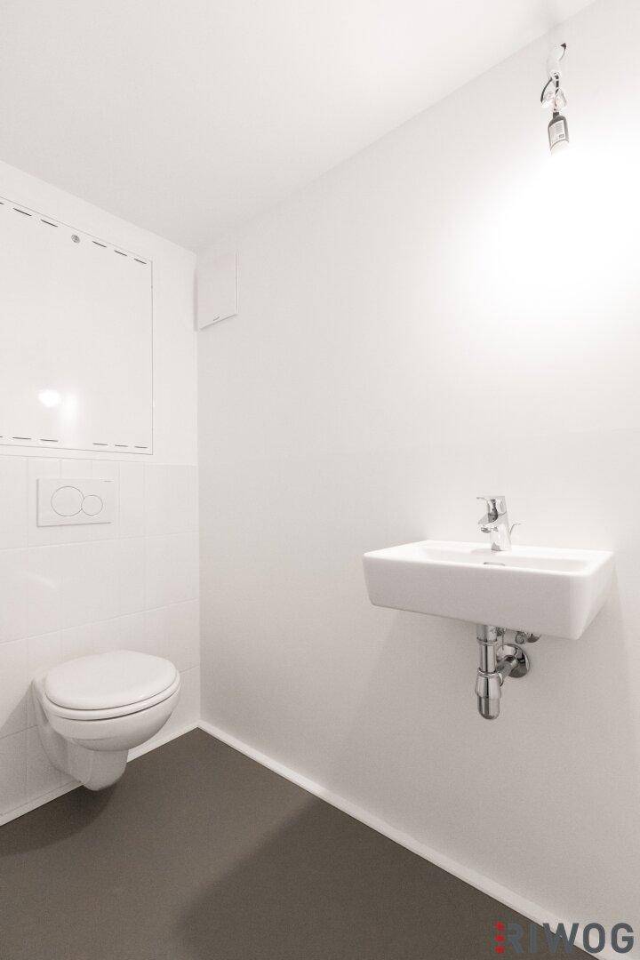 Modernes Gäste-WC mit wandhängender Toilette und kleinem Waschbecken.
