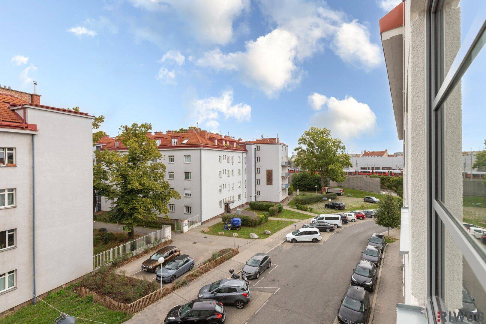 Weitläufiger Blick auf die Wohnstraße mit gepflegten Gebäuden und Grünflächen.