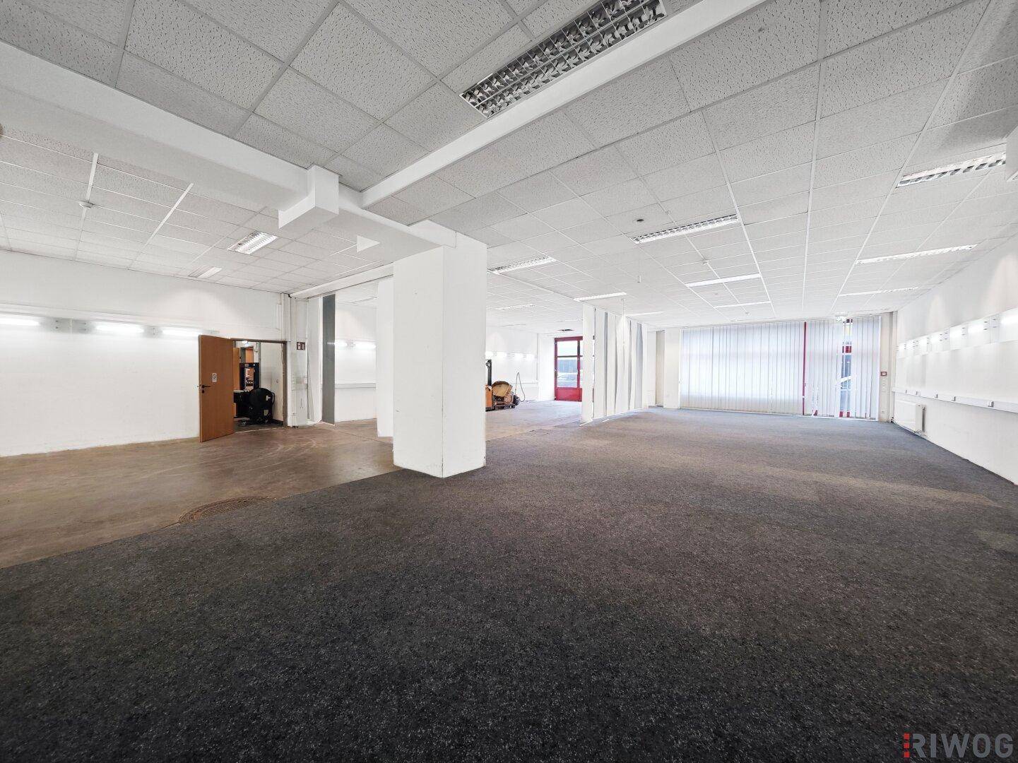 Weitläufiger Gewerberaum mit Teppichboden und Säulen, bietet viel Platz für verschiedene Nutzungskonzepte.
