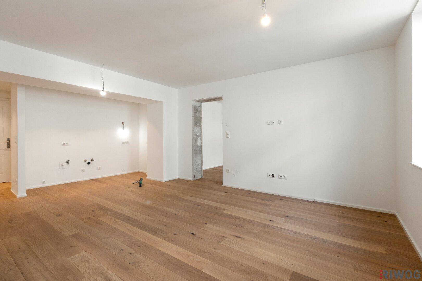 Leerer Raum mit Holzboden und weißen Wänden, ideal für eine individuelle Gestaltung.