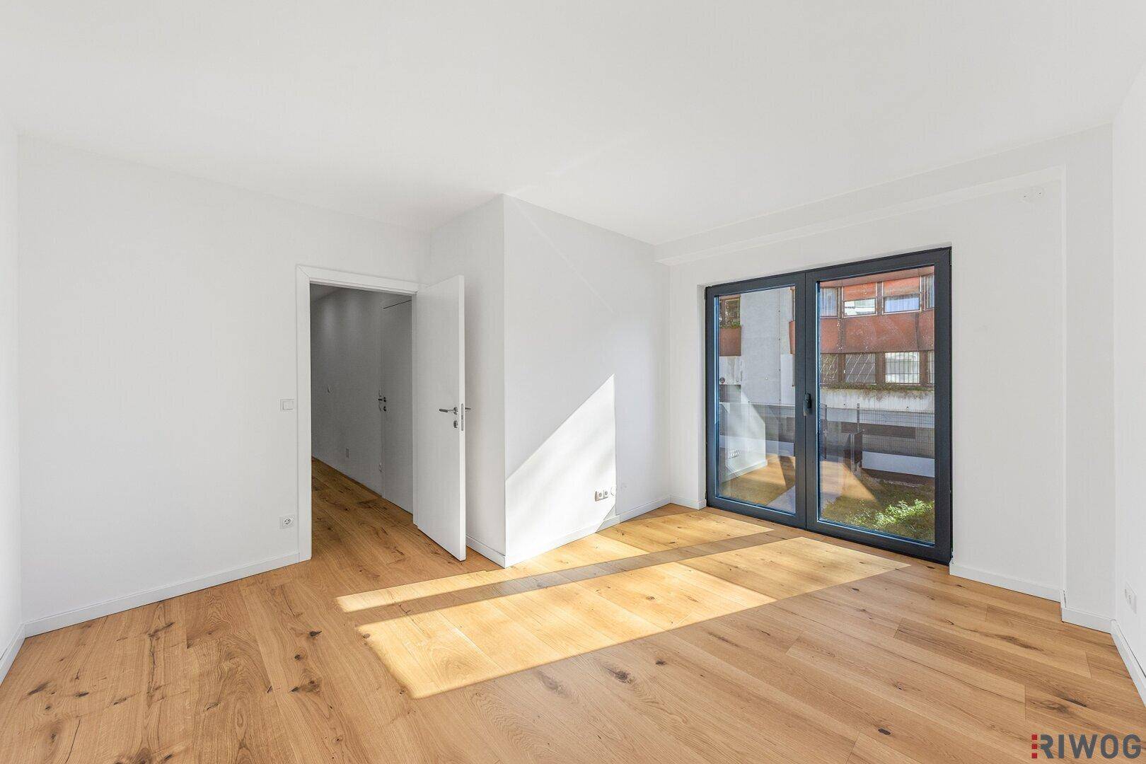 Geräumiges Schlafzimmer mit Eichenparkettboden und viel Tageslicht durch große Fenster.