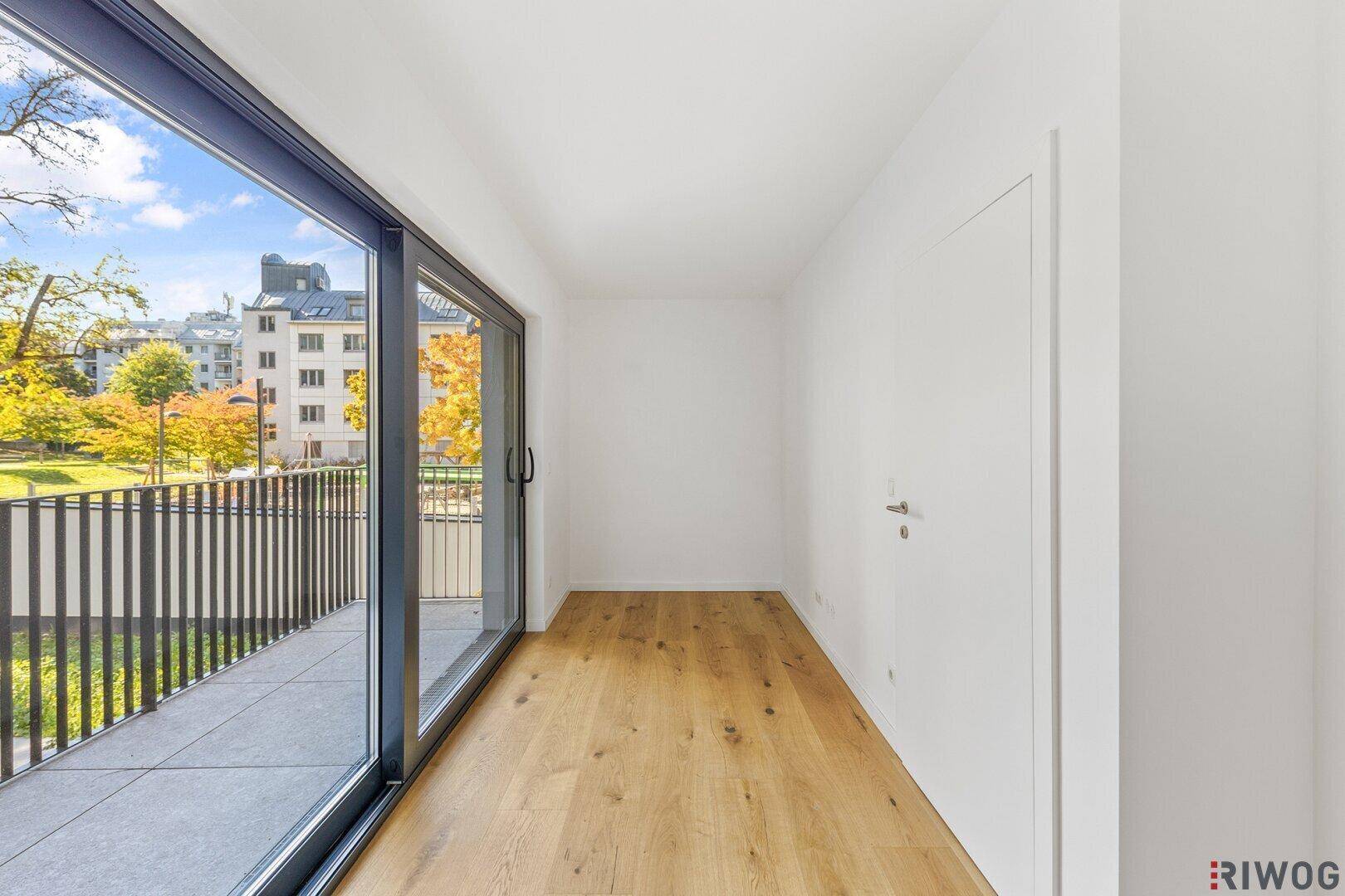 Helles Zimmer mit Eichenparkettboden und direktem Zugang zu einem Balkon.