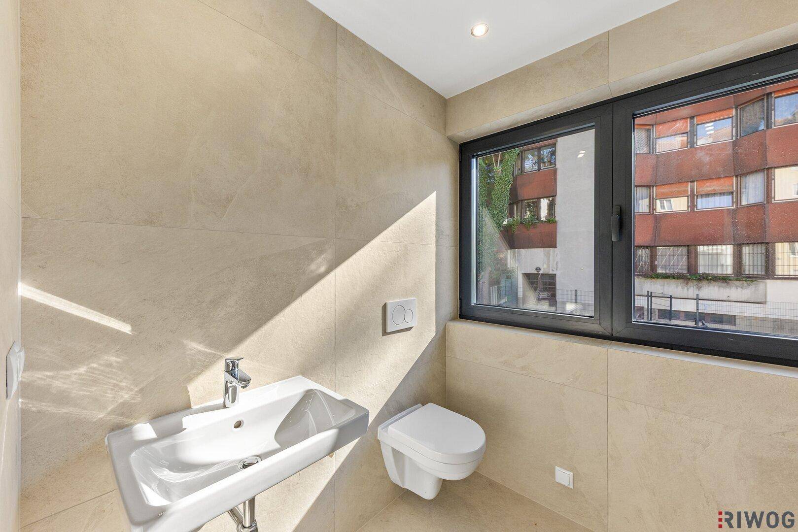 Helles Gäste-WC mit modernem Waschbecken, wandhängendem WC und Fenster.