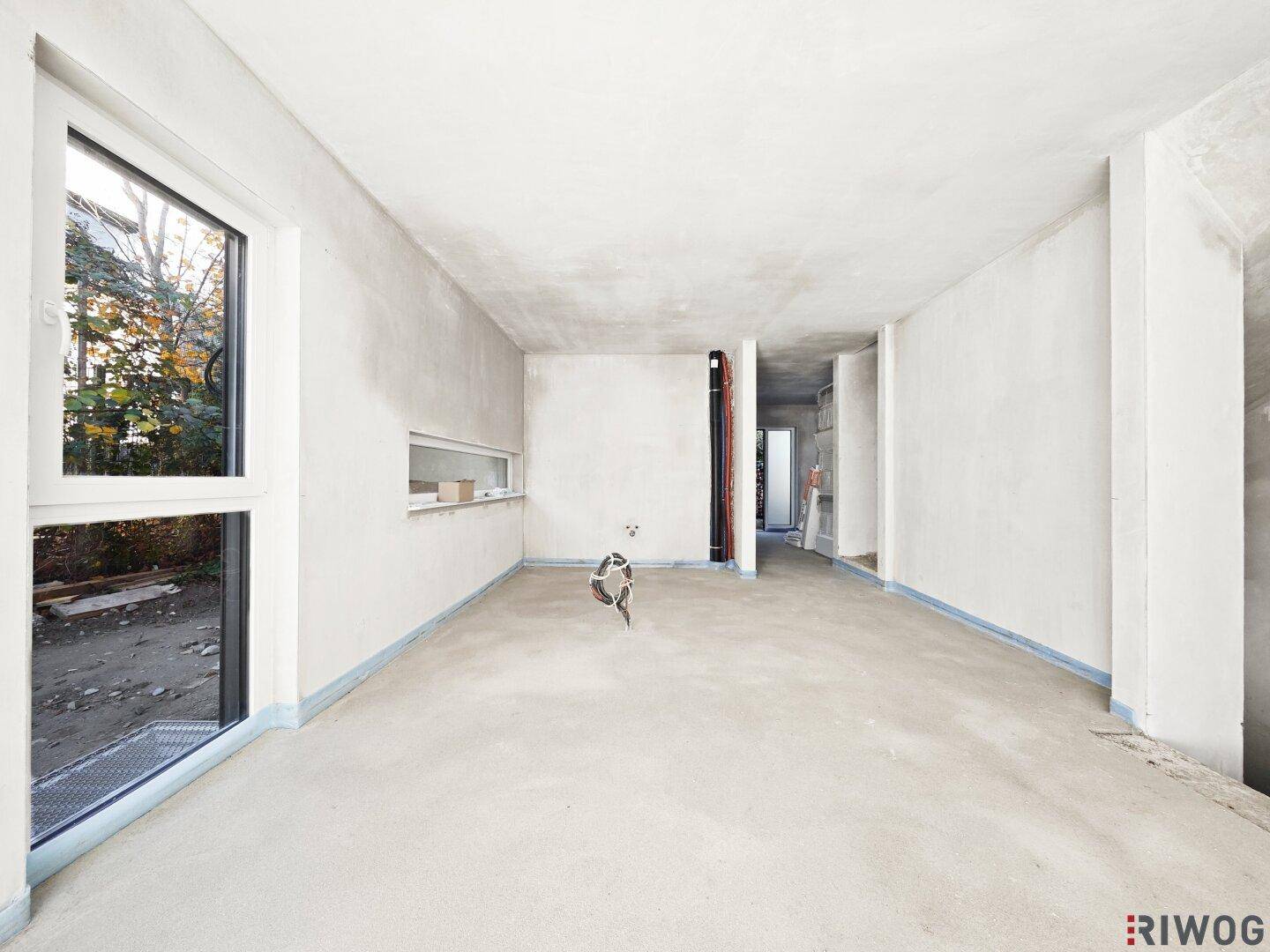 Heller, unfertiger Raum mit großem Fenster und Blick ins Freie, ideal für individuelle Gestaltung.