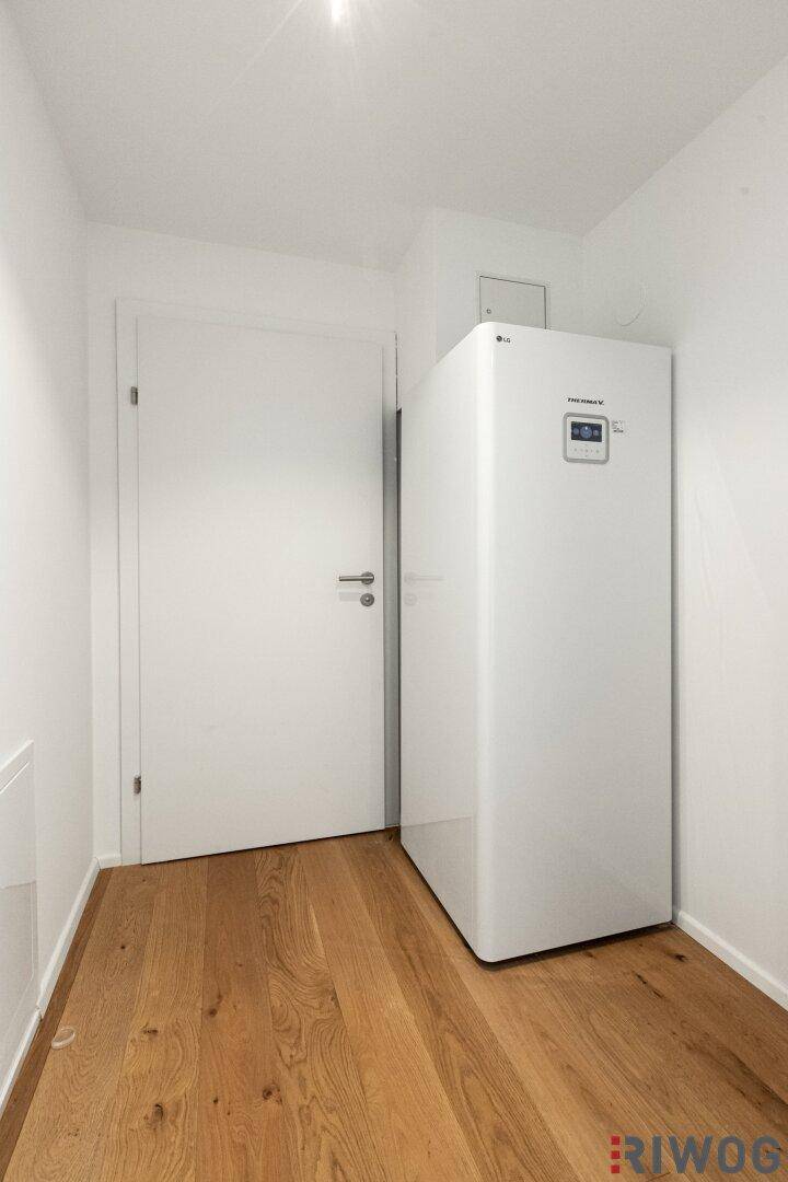 Kleiner Raum mit Wärmepumpe und Holzboden, möglicherweise ein Technikraum oder Abstellraum.
