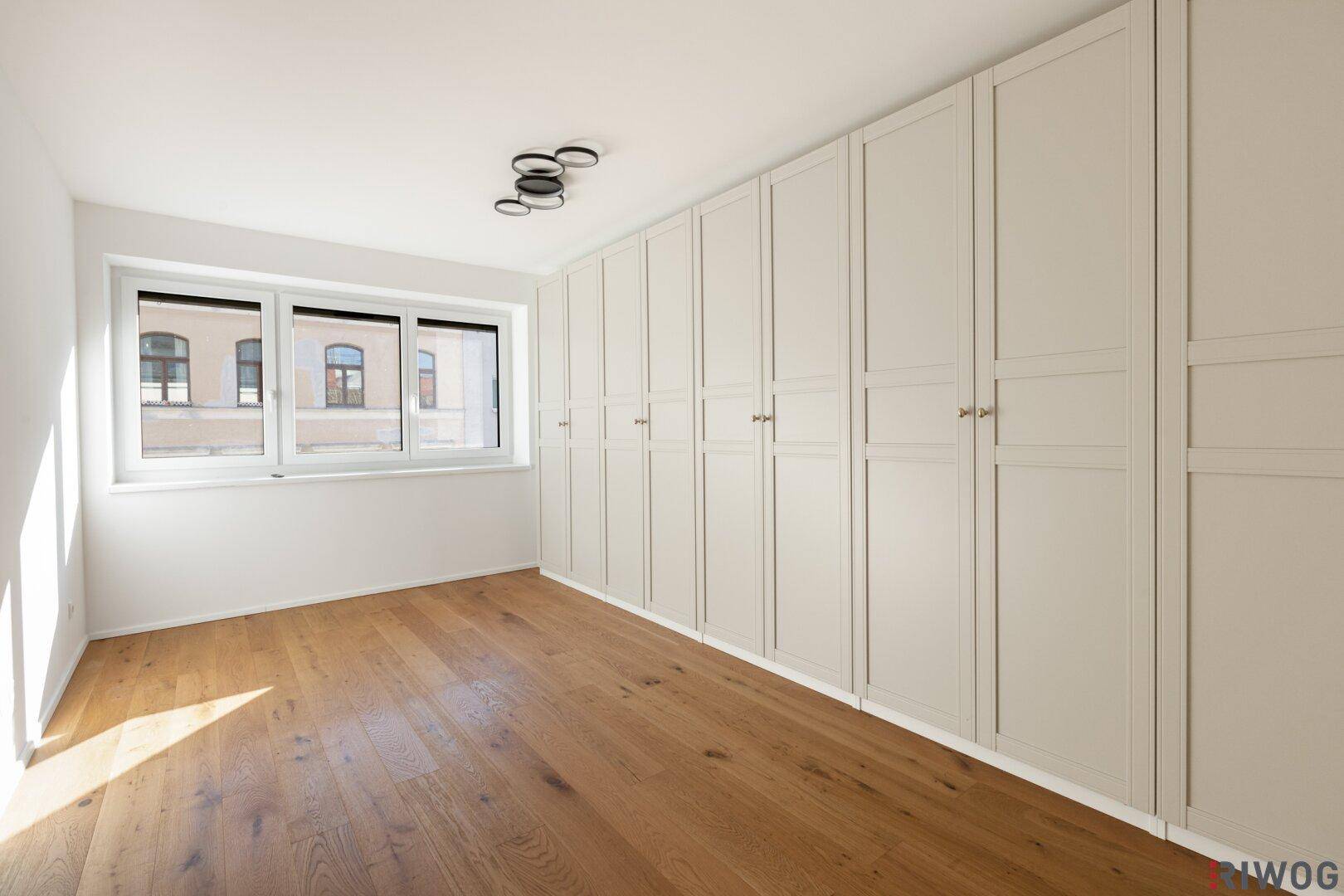 Helles Schlafzimmer mit Einbauschränken entlang einer Wand und Holzboden.