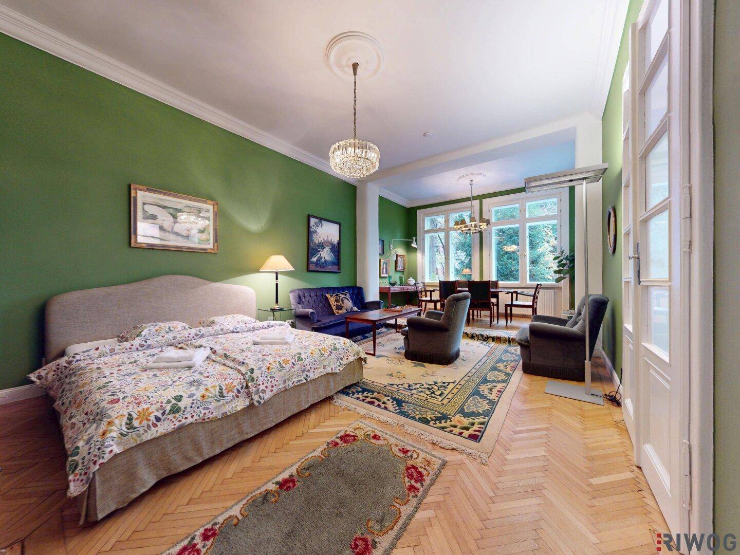 Helles Schlafzimmer mit Parkettboden, grünen Wänden und Zugang zum Essbereich.