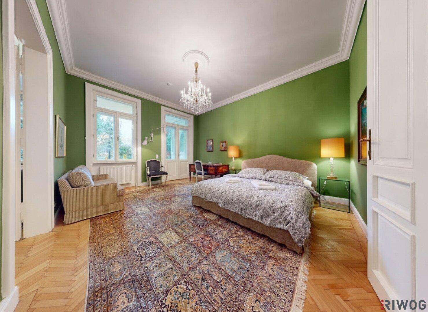 Geräumiges Schlafzimmer mit Parkettboden, grünen Wänden und großem Orientteppich.