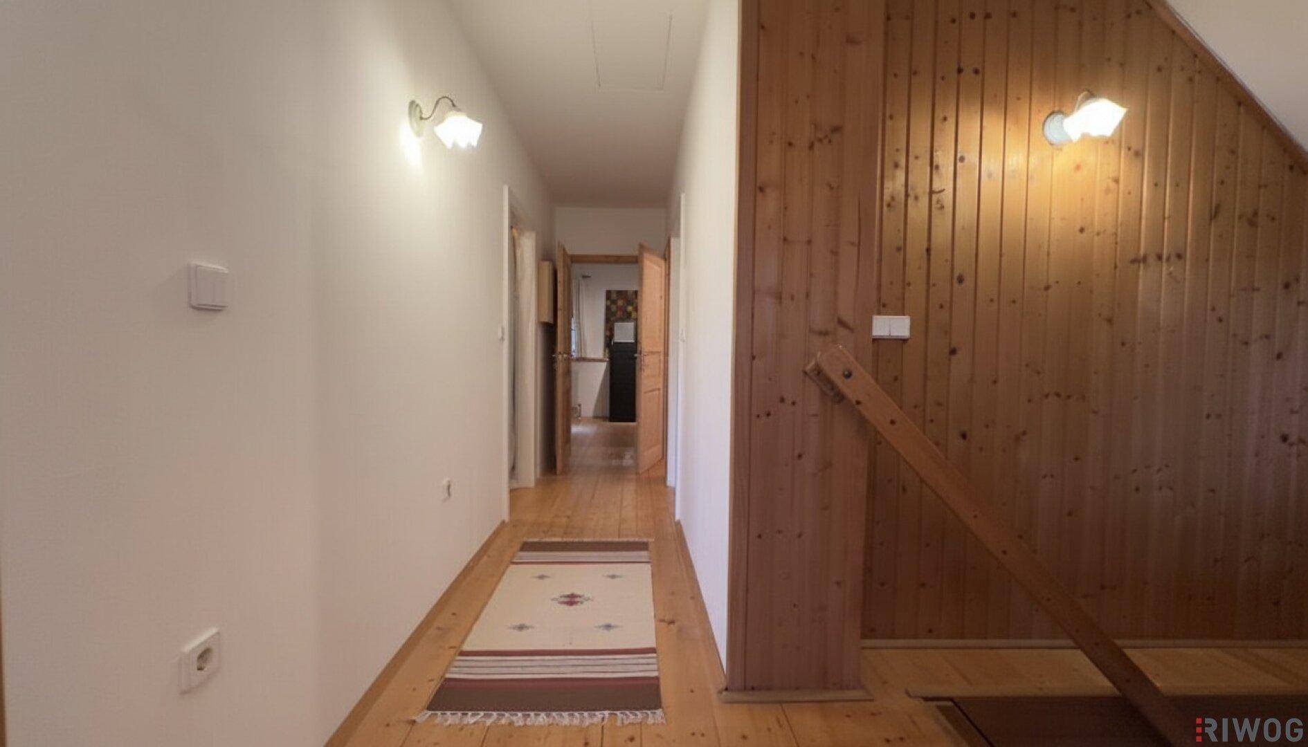 Flur mit Holzvertäfelung, Holzboden und einem Teppichläufer, der zu weiteren Räumen führt.