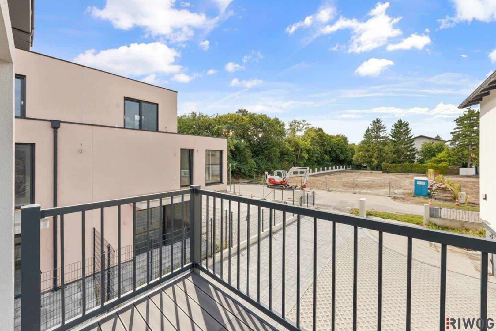 Balkon mit Blick auf die Umgebung, angrenzende Baustelle und grüne Bäume.