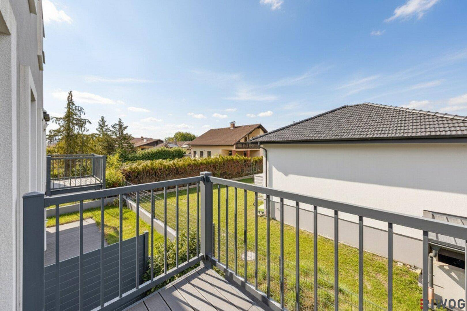 Balkon mit Blick auf einen gepflegten Garten und die umliegende Wohnbebauung.