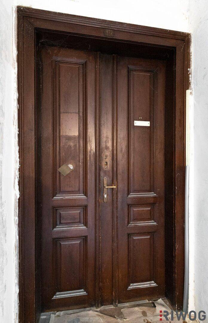 Klassische Holztür mit Kassetten und traditionellem Türgriff in einem Flur.