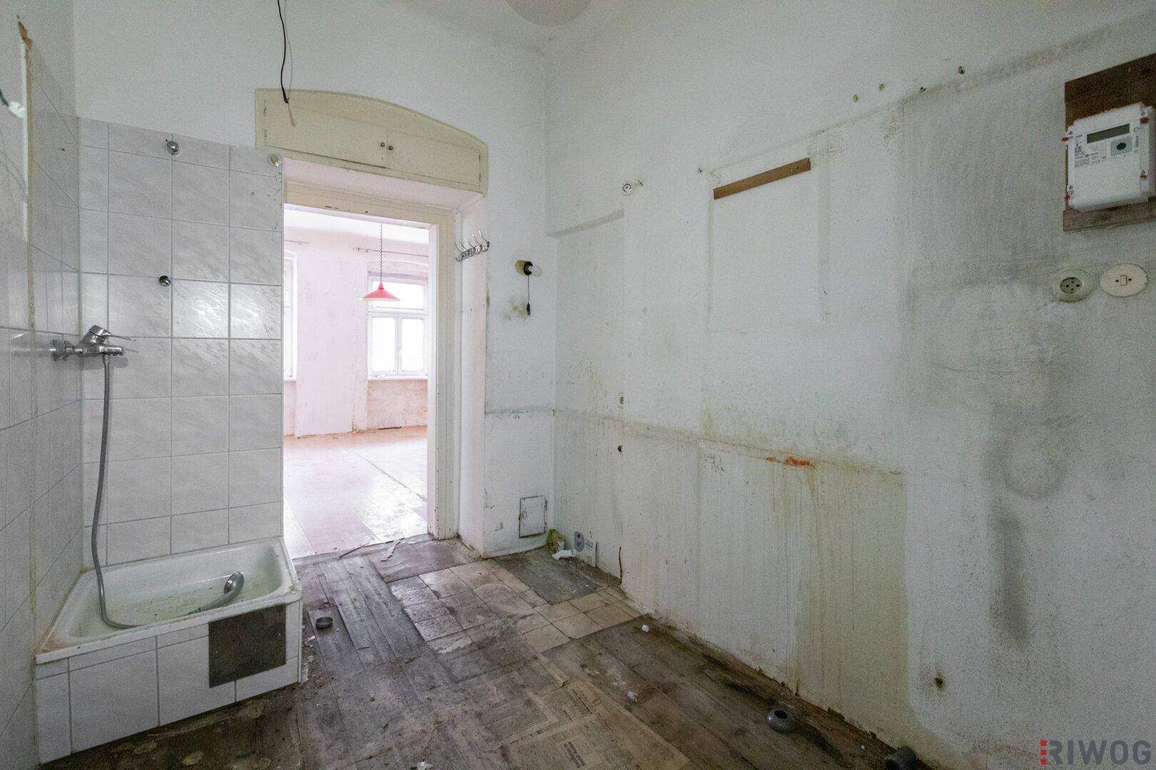 Badezimmer in Sanierungszustand mit alter Badewanne und Fliesen, bereit für eine Modernisierung.