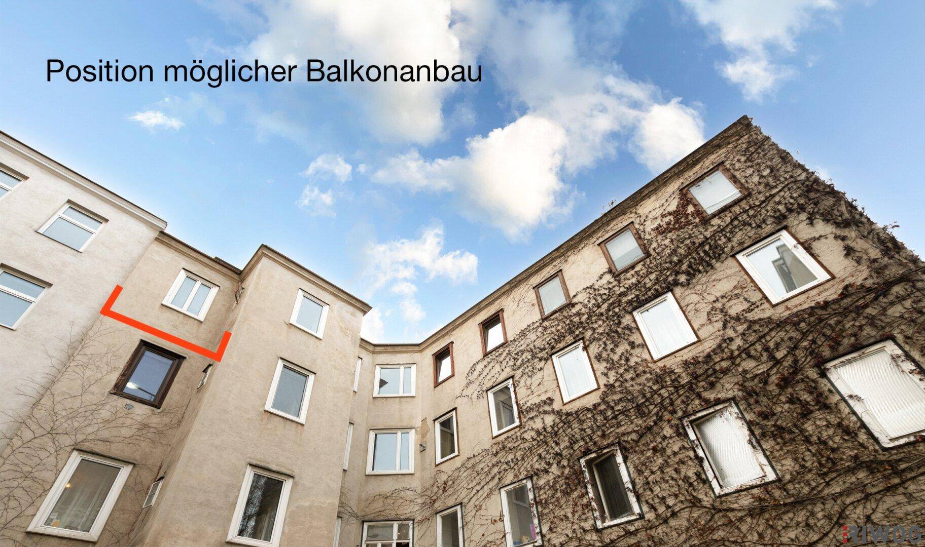 Blick in den begrünten Innenhof eines Altbaus, der die Position eines möglichen Balkonanbaus zeigt.
