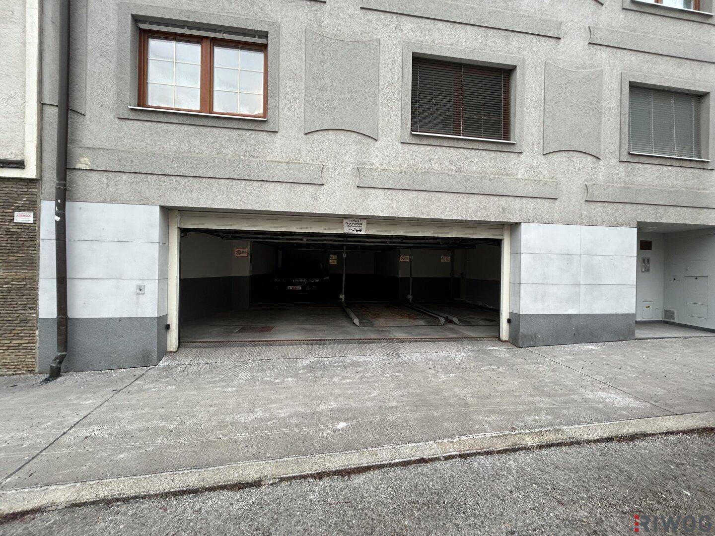 Nahaufnahme der offenen Garageneinfahrt mit Rampe, die zu einem unterirdischen Parksystem führt.