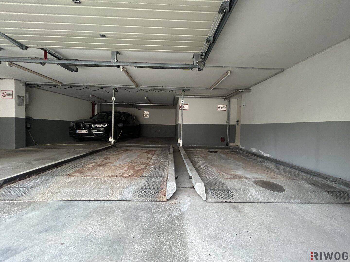 Weitere Innenansicht der Tiefgarage mit zwei Autohebebühnen und einem geparkten Fahrzeug im Hintergrund.