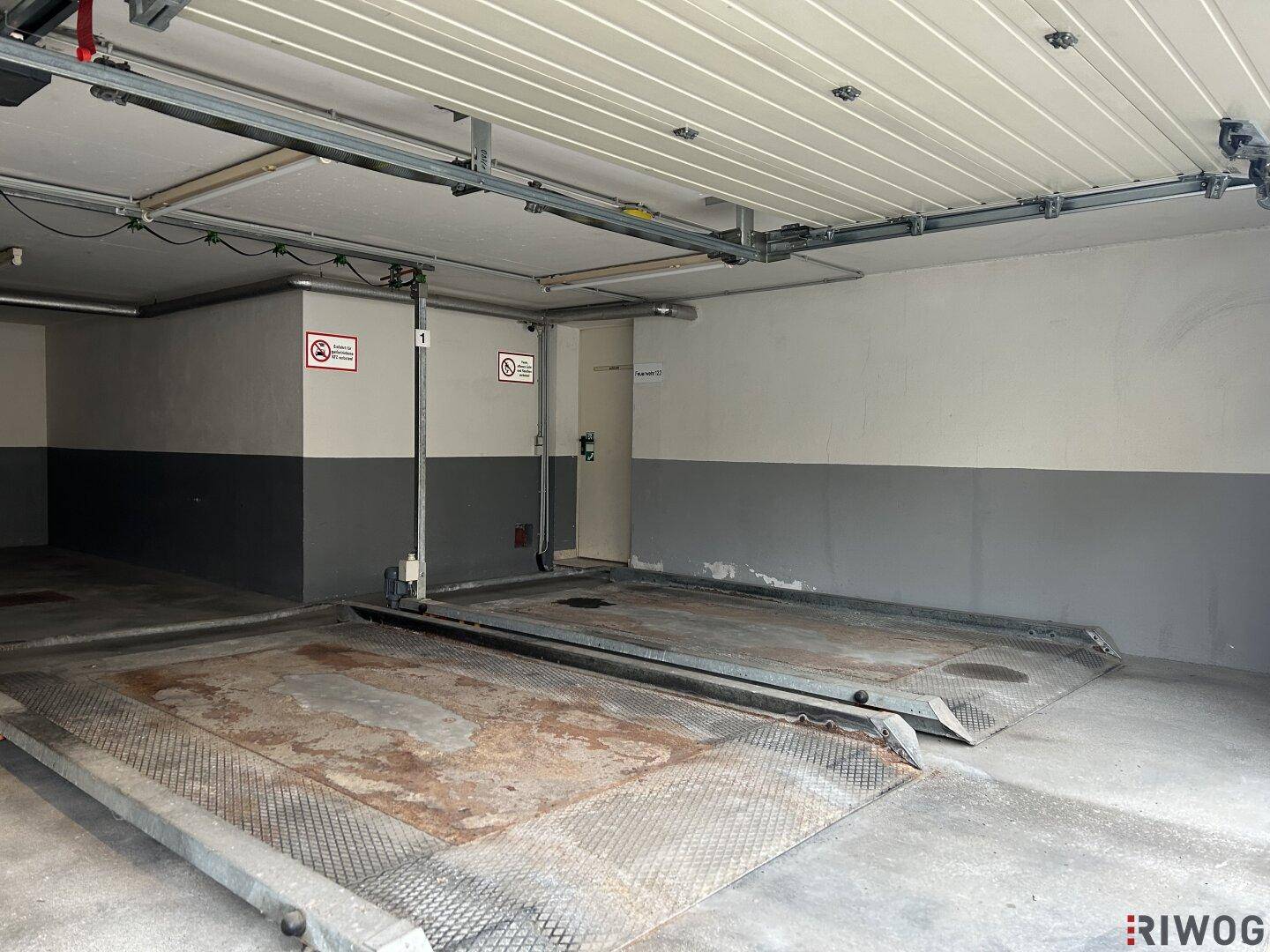 Innenansicht der Tiefgarage mit zwei leeren Autohebebühnen, bereit für weitere Fahrzeuge.
