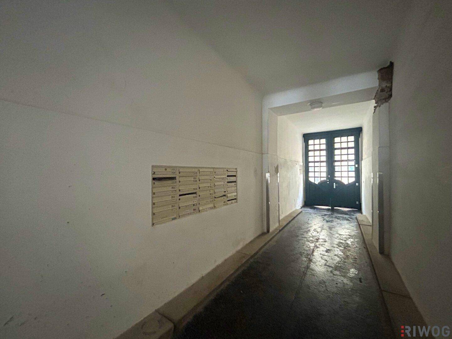 Eingangsbereich eines Gebäudes mit Briefkästen an der Wand und einer Rampe zum Ausgang.