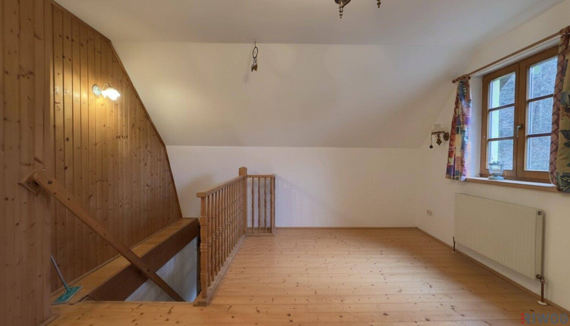 Offener Dachbodenbereich mit Holzvertäfelung, Holzboden und Treppenzugang.