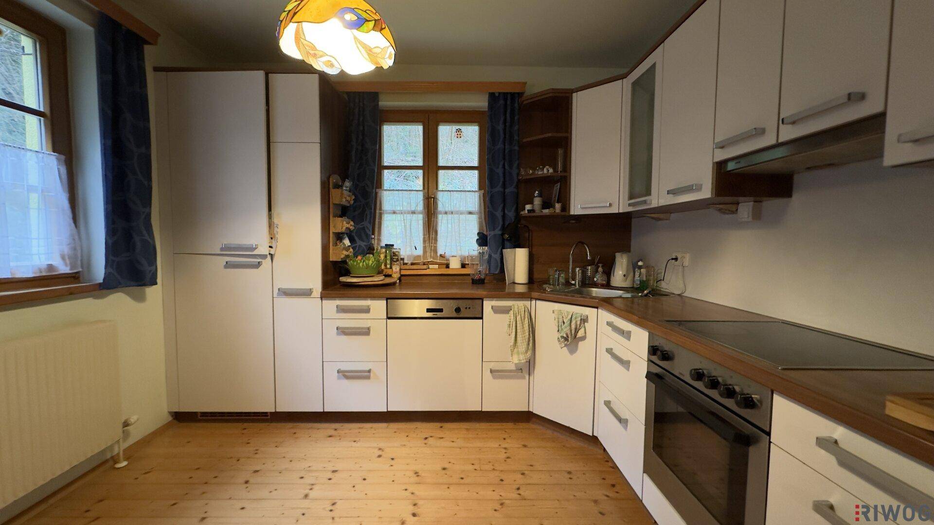 Funktionale Küche mit weißen Schränken, Holzarbeitsplatte und Holzboden.