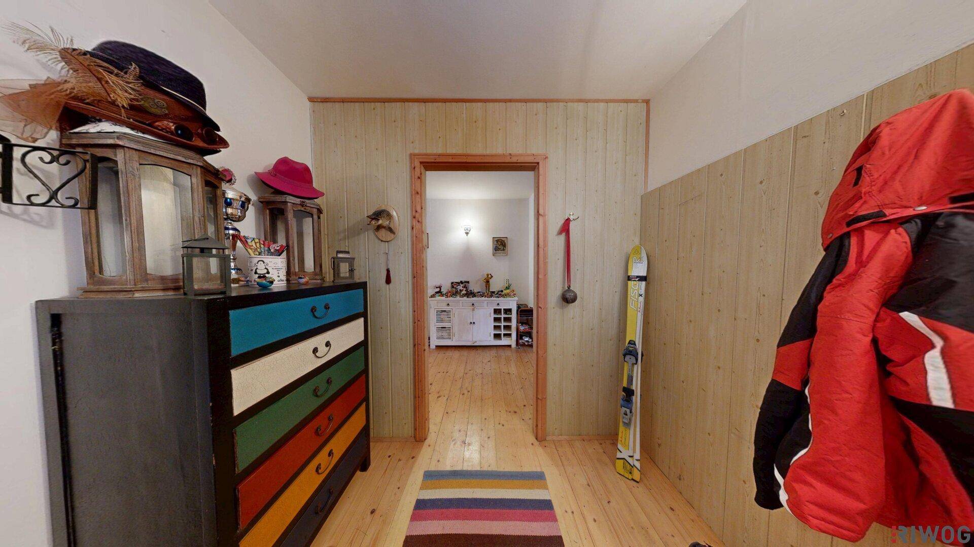 Einladender Flur mit Holzwänden, bunter Kommode und Platz für Sportausrüstung.