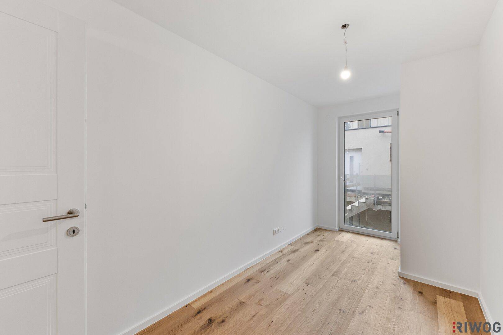 Helles Schlafzimmer mit Holzboden und Zugang zu einem kleinen Außenbereich.