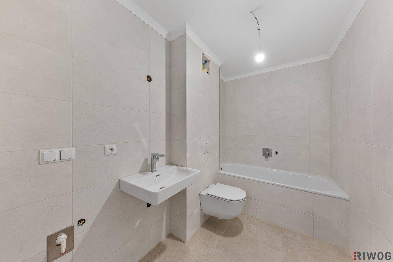 Helles Badezimmer mit Badewanne, wandhängendem WC und modernem Waschbecken.