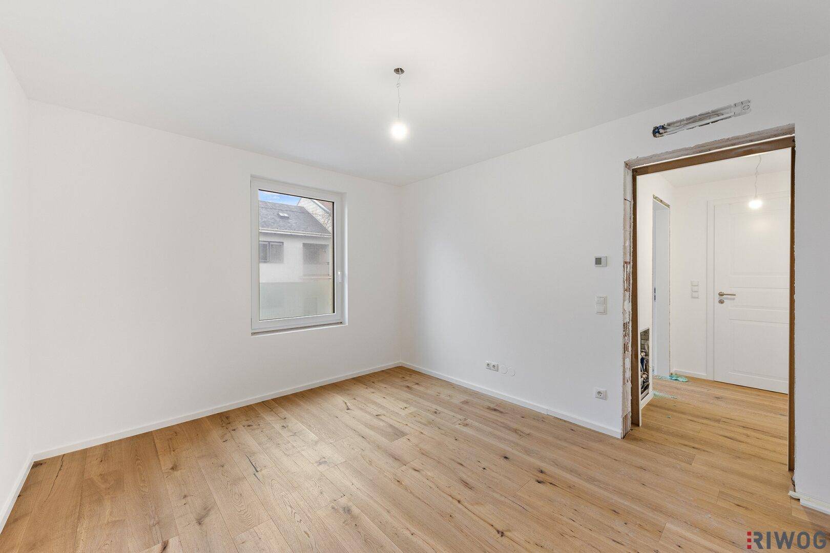 Modernes Zimmer mit Holzboden und Fenster, das einen Blick nach draußen ermöglicht.