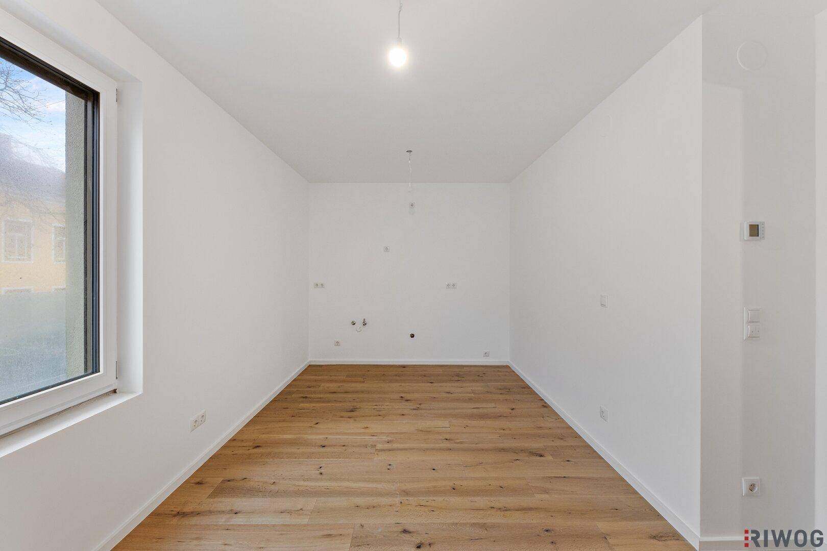 Geräumiges Zimmer mit Holzboden und weiß gestrichenen Wänden, ideal für ein Schlafzimmer.