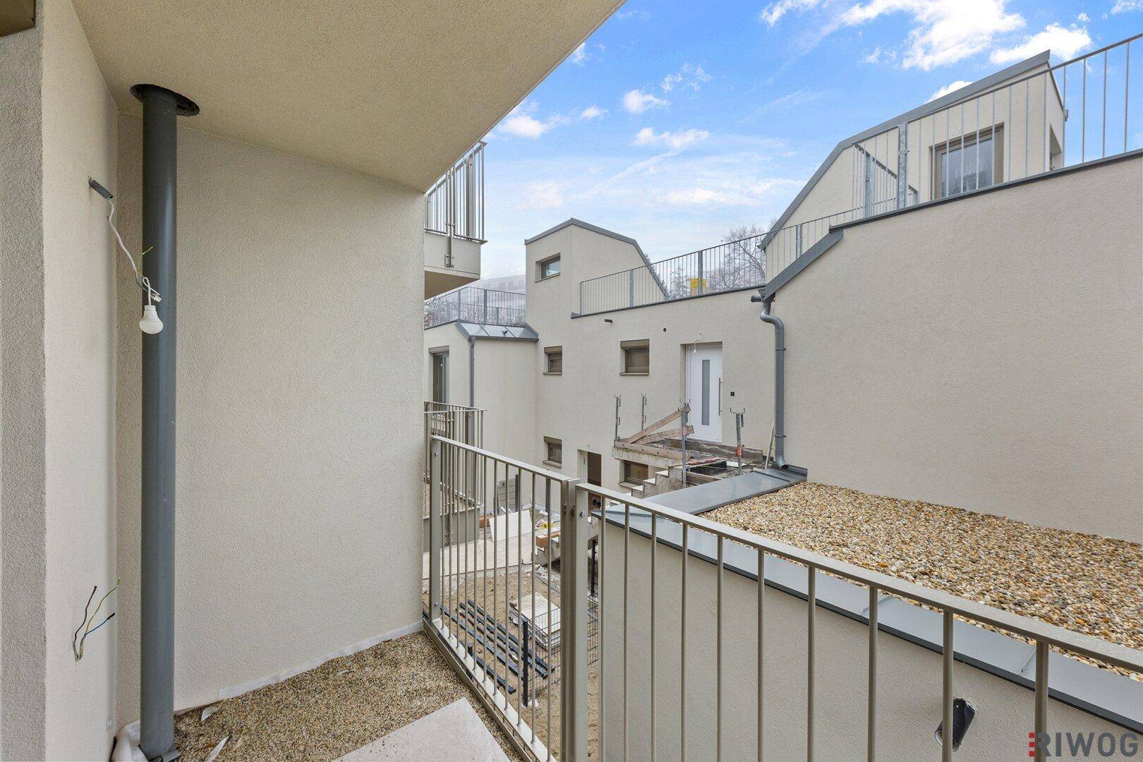 Blick von einem Balkon auf den Innenhof mit weiteren Gebäudeteilen und Bauelementen.