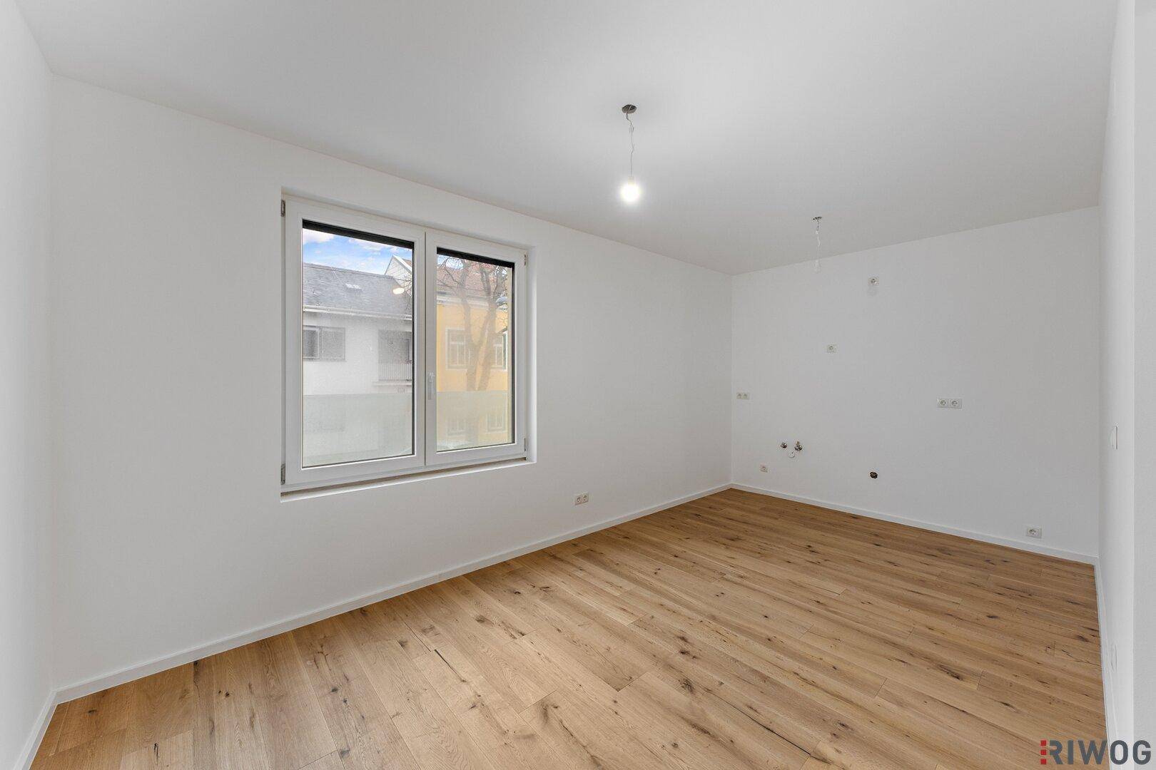 Geräumiges Zimmer mit hellem Holzfußboden und großem Fenster für viel Tageslicht.
