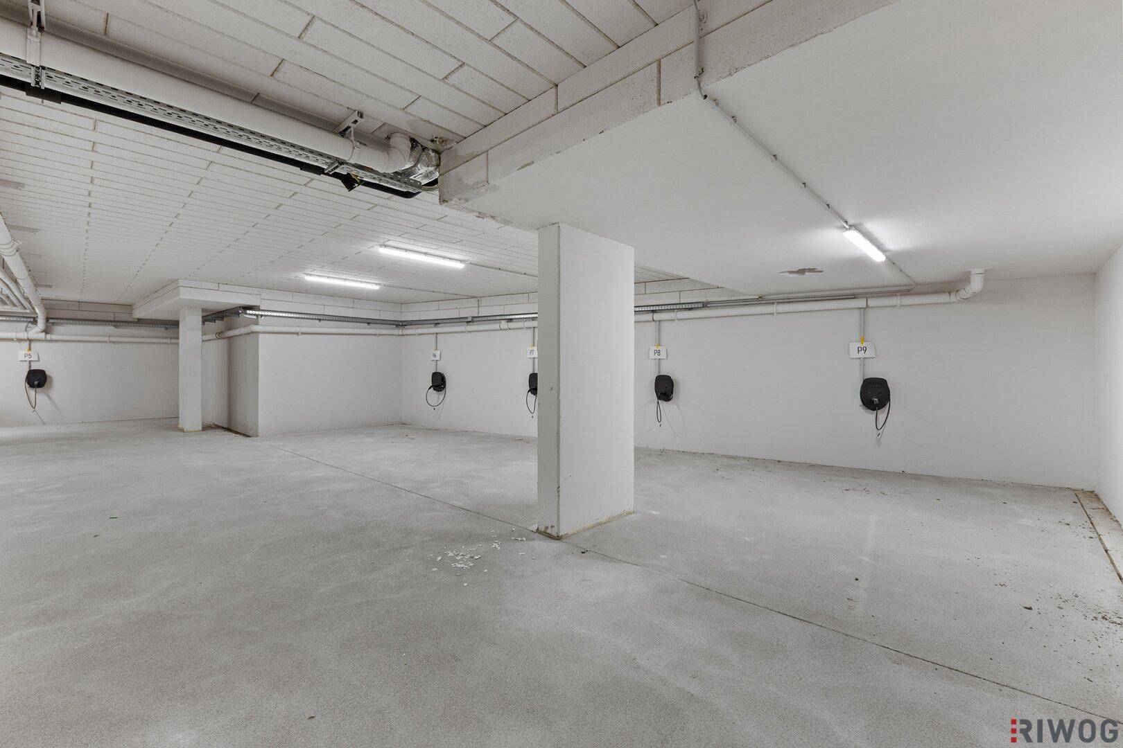 Geräumige Tiefgarage mit mehreren Stellplätzen und Ladestationen für Elektrofahrzeuge.