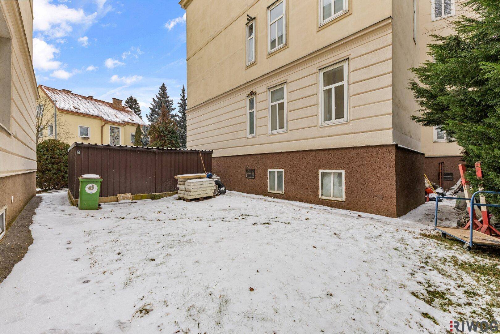 Kleiner Gartenbereich neben dem Gebäude, bedeckt mit Schnee, bietet Potenzial für Gestaltung.
