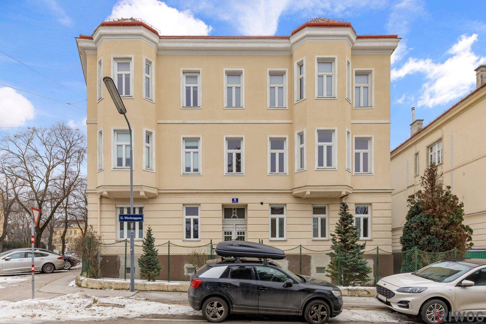 Klassische Altbaufassade mit vielen Fenstern und dekorativen Elementen an einem sonnigen Wintertag.