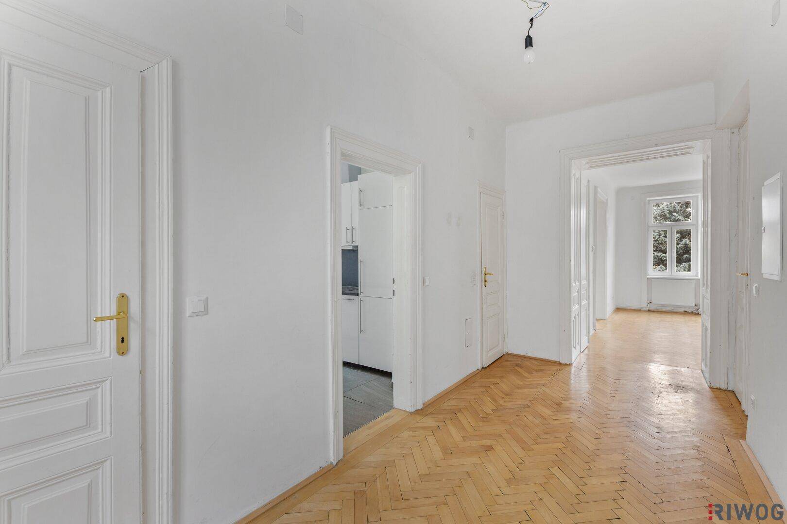 Langer Flur mit Fischgrätparkett, der mehrere Zimmer verbindet.