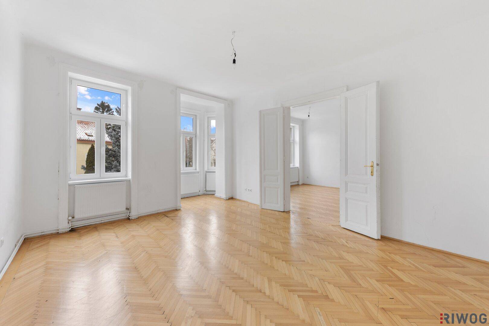 Geräumiges Zimmer mit klassischem Fischgrätparkett und Blick ins Grüne.