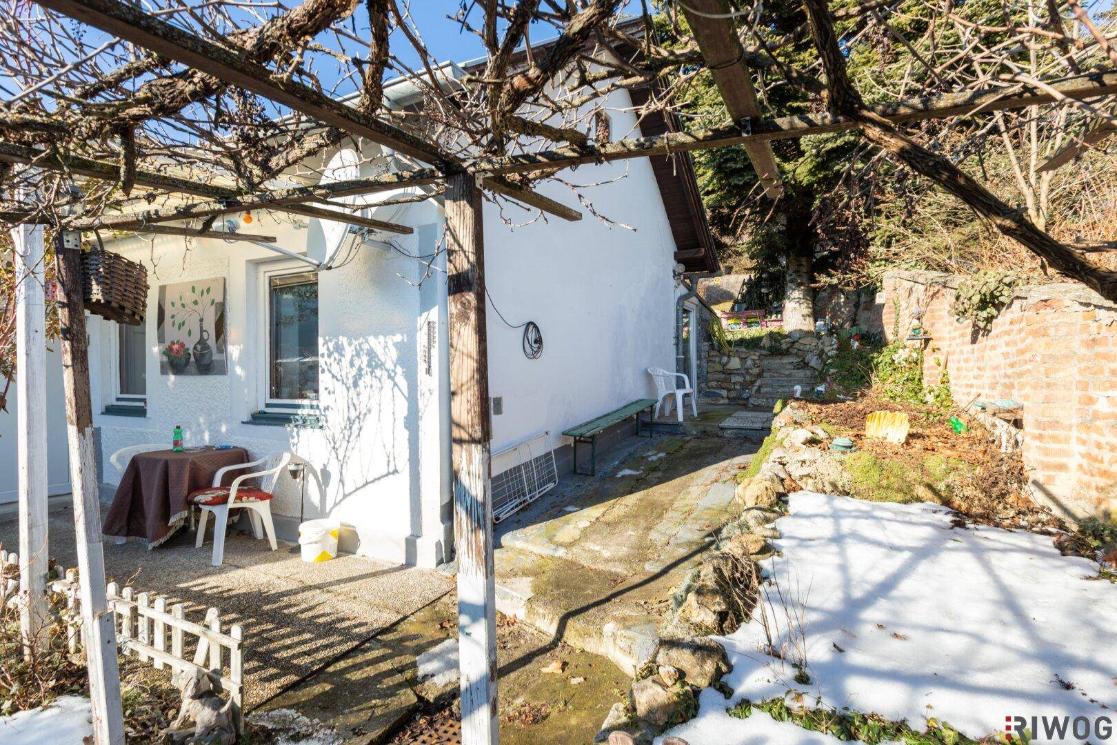 Überdachte Terrasse mit Sitzgelegenheit und Blick auf den Garten, teilweise mit Schnee bedeckt.
